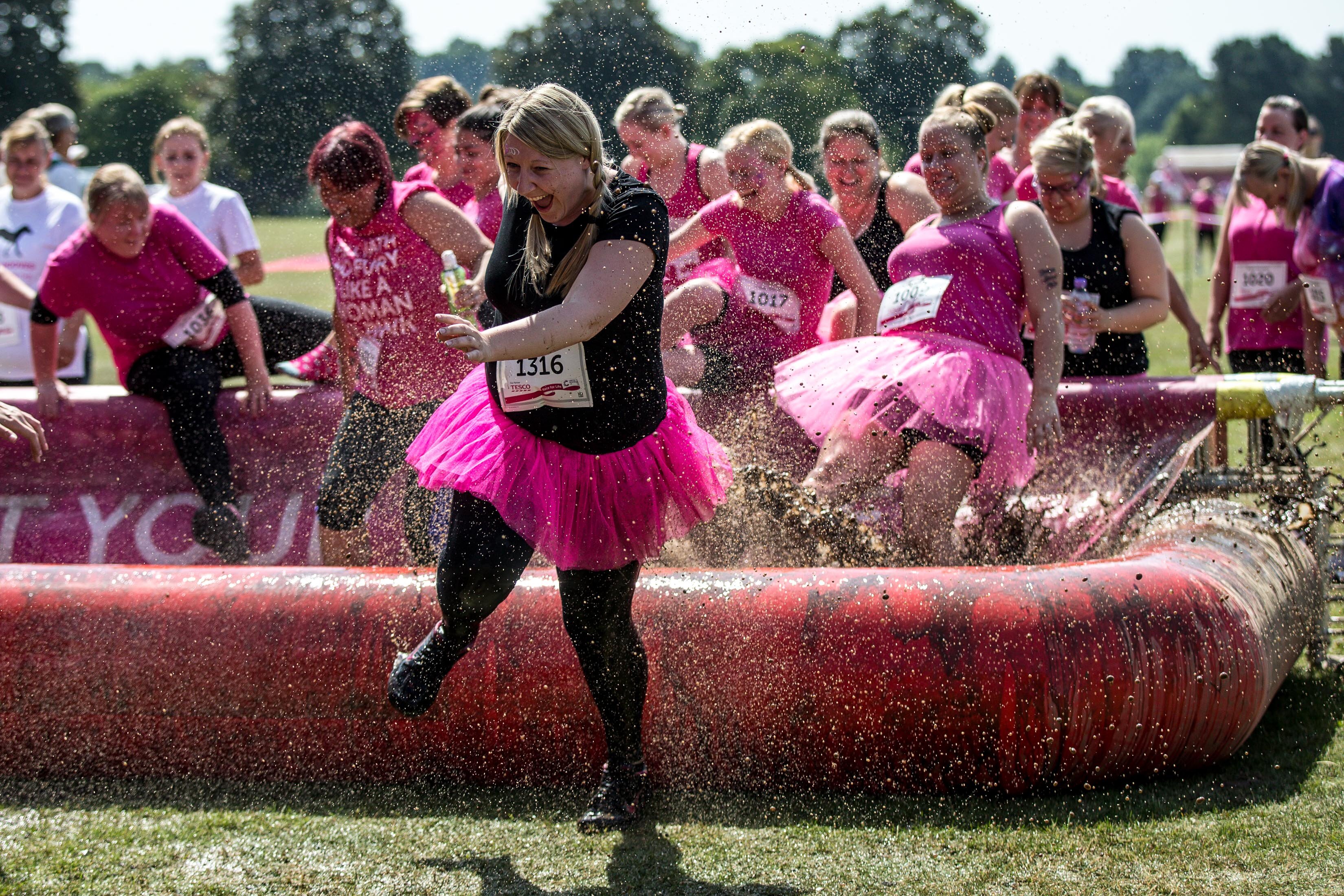 Participants race through a muddy obstacle during the Muddy Runs Sheffield Race For Life 5k, 10k, Pretty Muddy, Pretty Muddy Kids